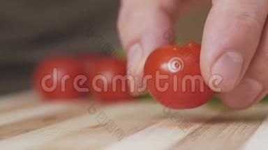 一个女人在分割的木板上用刀切一个樱桃番茄。